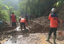 Pasca Longsor Petugas Bersihkan Material Tanah dengan Alat Seadanya